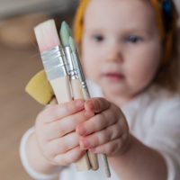 Child holding paint brushes - Inspire & Play Early Learning - Endeavour Hills