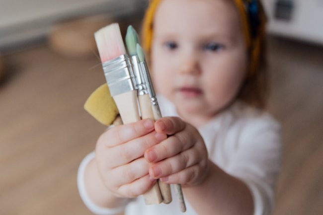 Child holding paint brushes - Inspire & Play Early Learning - Endeavour Hills